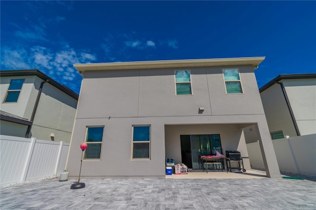 back of property with a patio, fence, and stucco siding