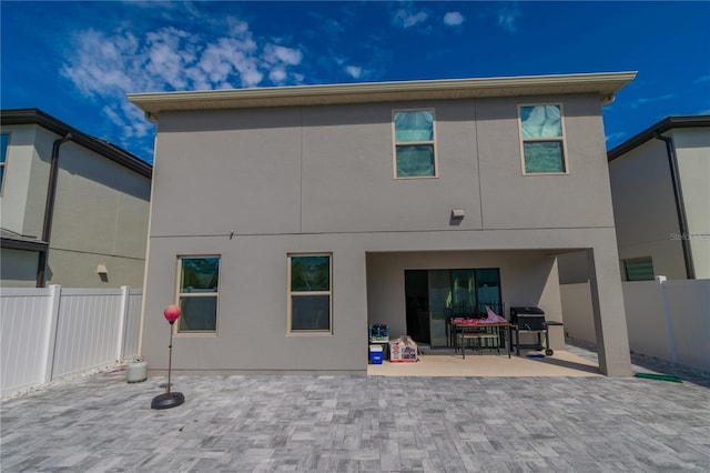 rear view of property with a patio, fence, and stucco siding