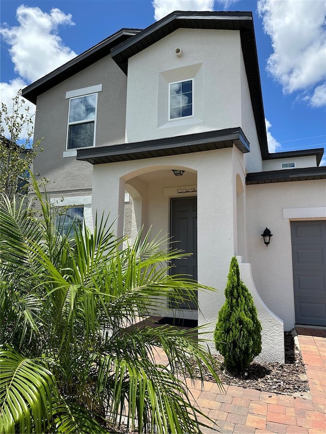 view of exterior entry featuring an attached garage and stucco siding