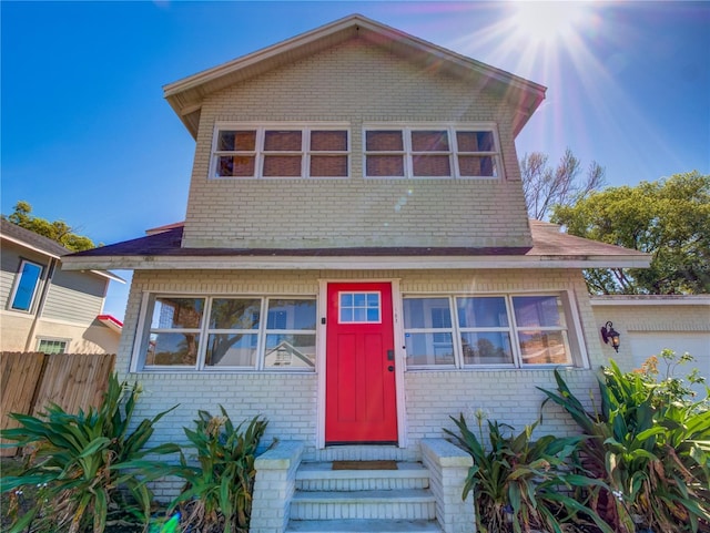 view of front of house featuring brick siding and fence