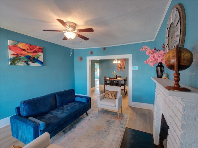 living area with baseboards, wood finished floors, a textured ceiling, crown molding, and a brick fireplace