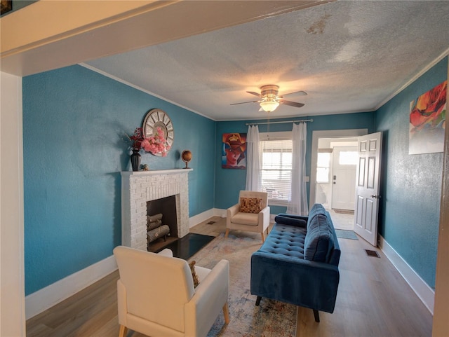 living area featuring a textured ceiling, a textured wall, a fireplace, wood finished floors, and baseboards