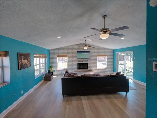 living area with a textured ceiling, a textured wall, vaulted ceiling, and wood finished floors