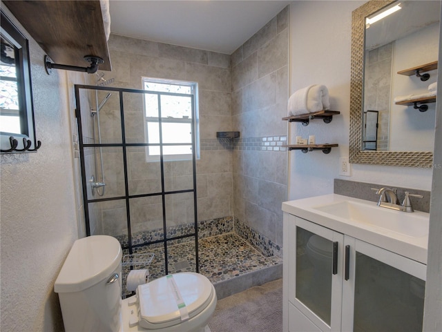 full bathroom with a textured wall, a stall shower, vanity, and toilet