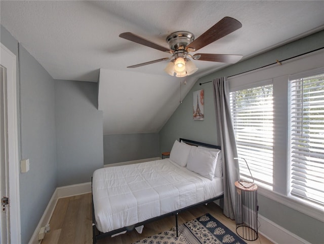 bedroom with baseboards, vaulted ceiling, and wood finished floors