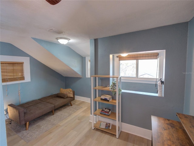 sitting room featuring baseboards, visible vents, vaulted ceiling, and wood finished floors