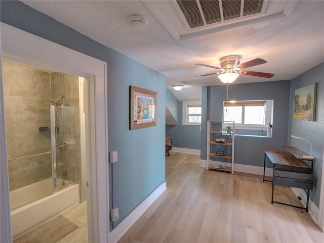 interior space with light wood-style floors, visible vents, a textured ceiling, and baseboards