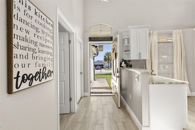 hallway featuring light wood-type flooring and baseboards