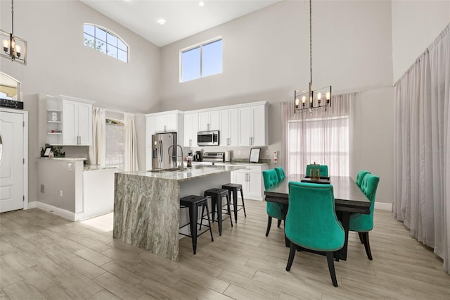 kitchen featuring white cabinets, an inviting chandelier, light wood-type flooring, and stainless steel appliances