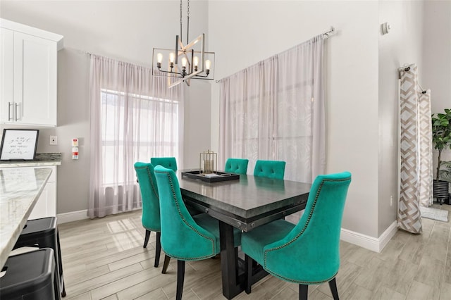 dining room with a chandelier, light wood-style flooring, and baseboards