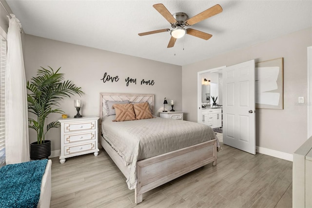 bedroom featuring baseboards, connected bathroom, a ceiling fan, and light wood-style floors