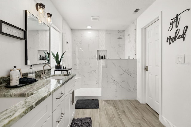 full bath with wood tiled floor, visible vents, vanity, and a marble finish shower