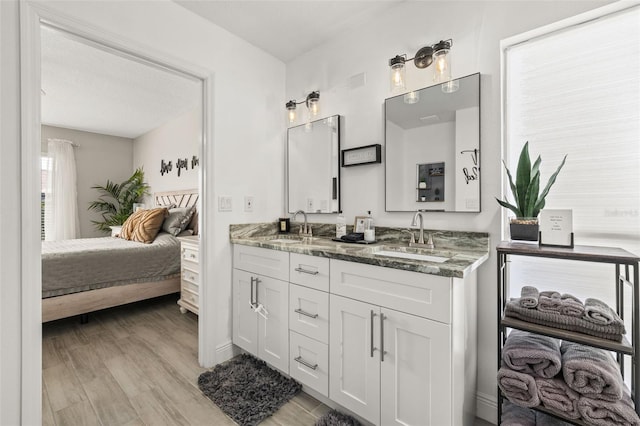 bathroom with ensuite bathroom, double vanity, wood finished floors, and a sink