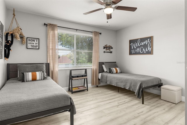 bedroom featuring ceiling fan, baseboards, and wood finished floors