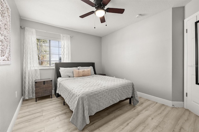 bedroom featuring ceiling fan, a textured ceiling, baseboards, and wood finished floors