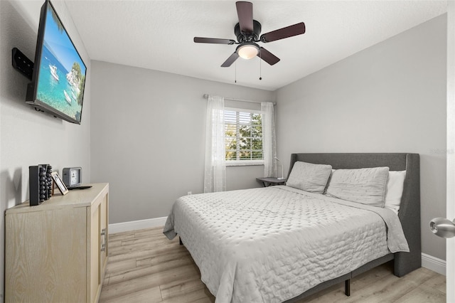 bedroom with ceiling fan, light wood finished floors, and baseboards