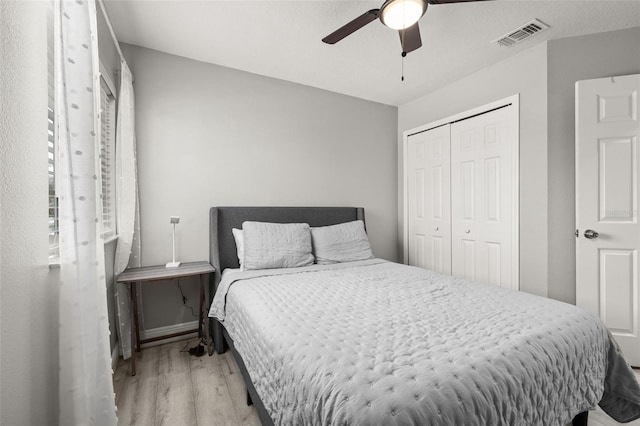 bedroom with ceiling fan, a closet, wood finished floors, and visible vents