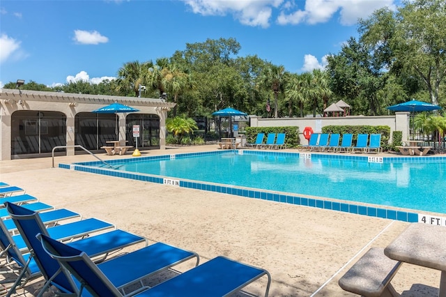 community pool with a patio area, fence, and a pergola