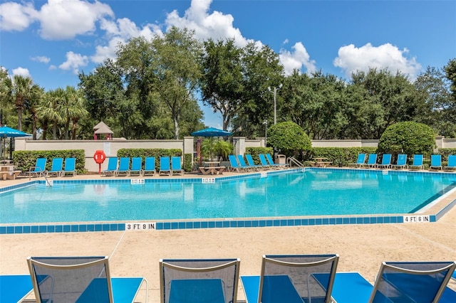 community pool with a patio area and fence