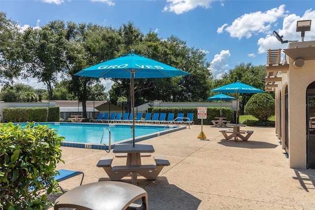 community pool with a patio and fence