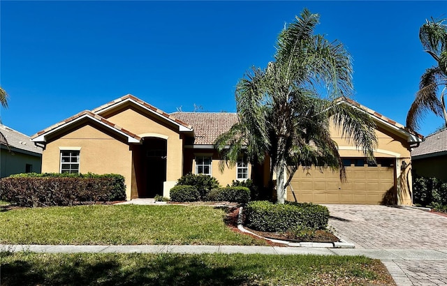 ranch-style home with a tiled roof, an attached garage, decorative driveway, a front lawn, and stucco siding