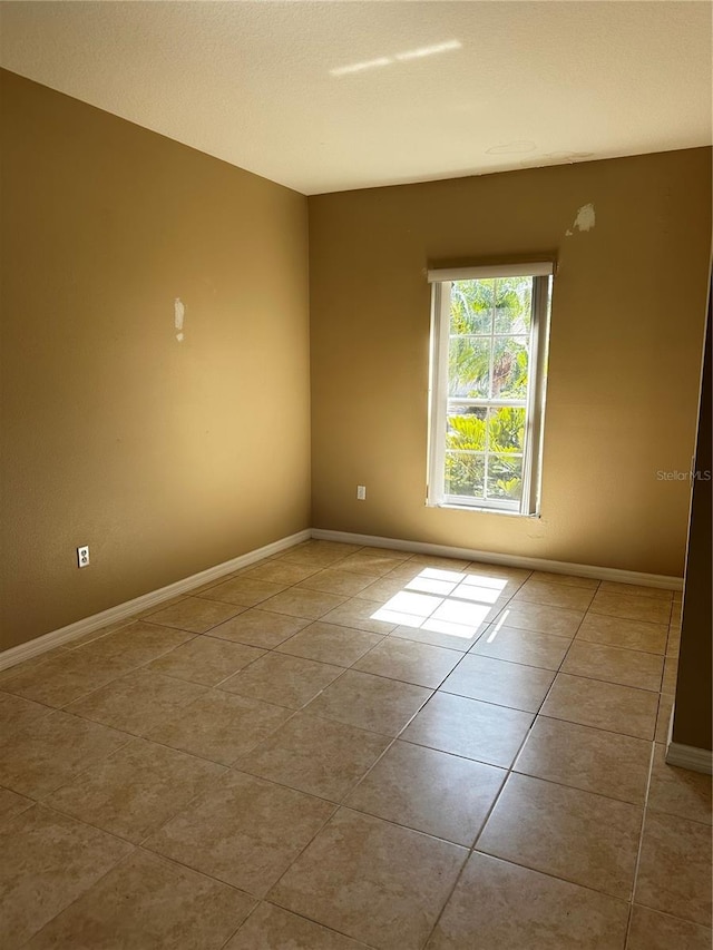 empty room with tile patterned flooring and baseboards