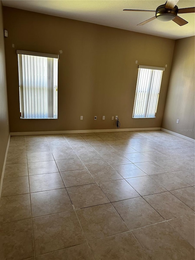 empty room featuring baseboards, a ceiling fan, and tile patterned floors