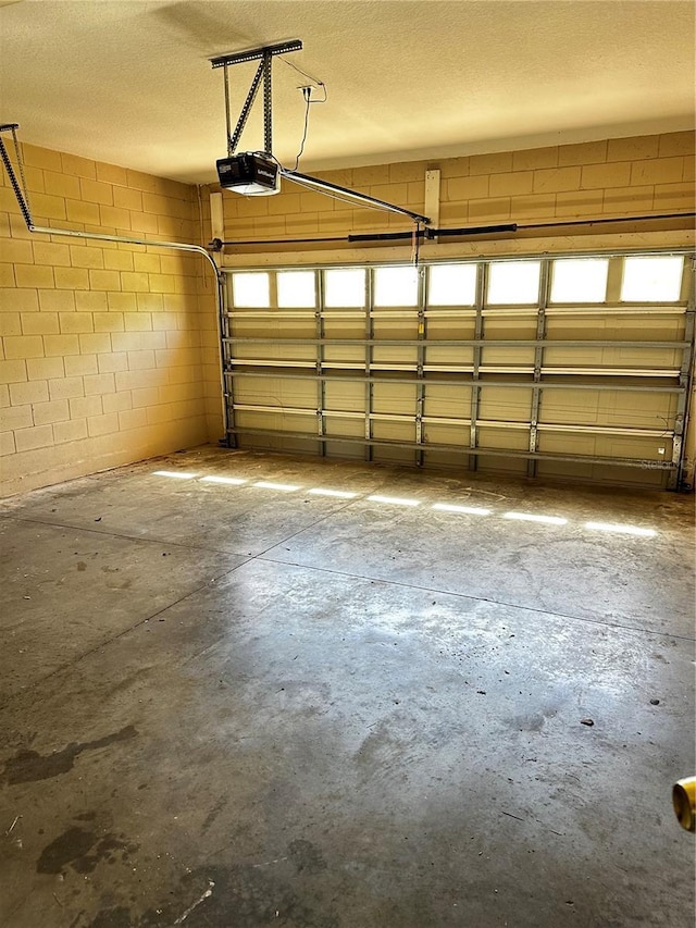 garage featuring a garage door opener and concrete block wall