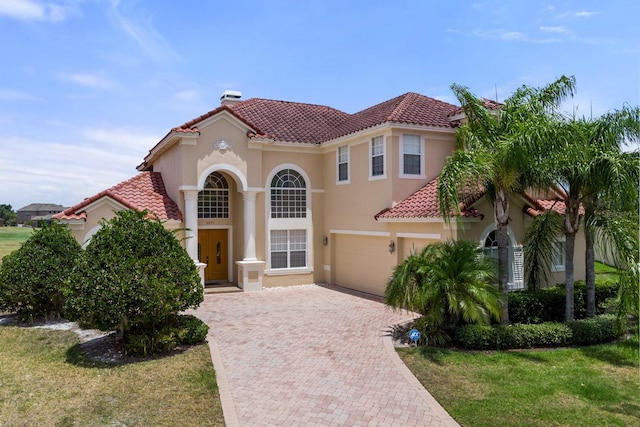 mediterranean / spanish home with a tiled roof, a front lawn, decorative driveway, and stucco siding