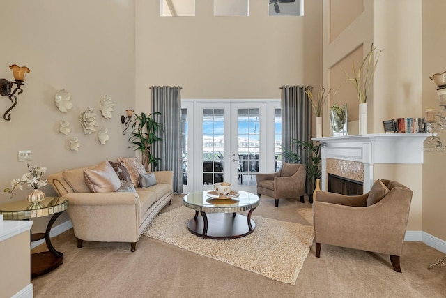 living area with french doors, a fireplace, a high ceiling, light carpet, and baseboards