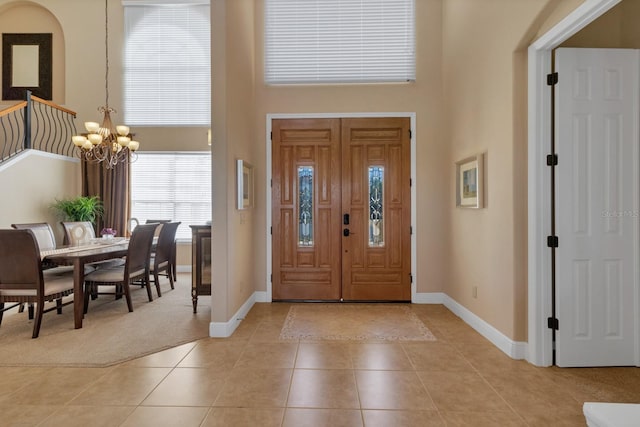 foyer featuring light tile patterned floors, a notable chandelier, light carpet, a high ceiling, and baseboards