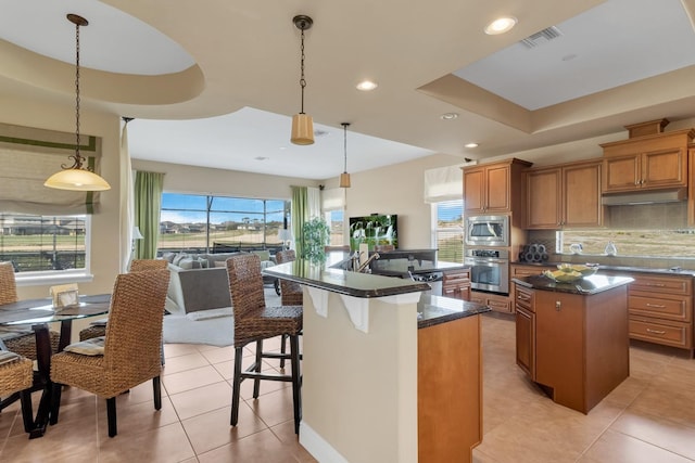 kitchen with visible vents, a center island with sink, appliances with stainless steel finishes, and brown cabinetry