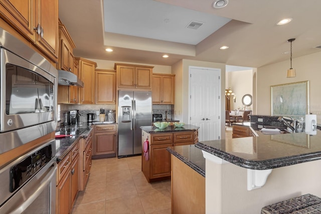 kitchen featuring stainless steel appliances, a spacious island, visible vents, a sink, and under cabinet range hood