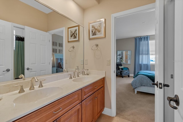 ensuite bathroom with ensuite bathroom, double vanity, a sink, and baseboards