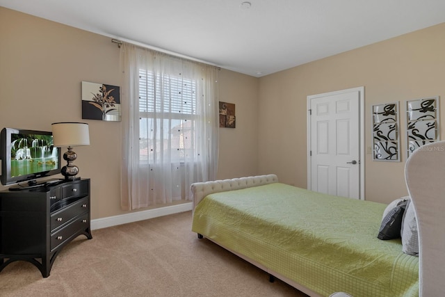 bedroom featuring light carpet and baseboards