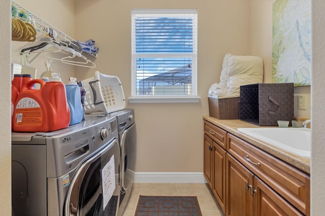 laundry area featuring light tile patterned floors, washing machine and dryer, a sink, baseboards, and cabinet space