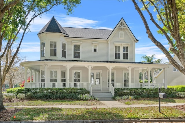 victorian home with a standing seam roof, a porch, roof with shingles, and metal roof