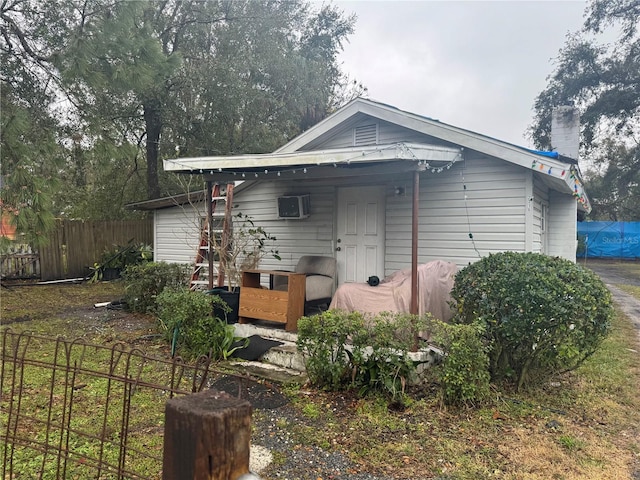 rear view of house with fence and a wall mounted air conditioner