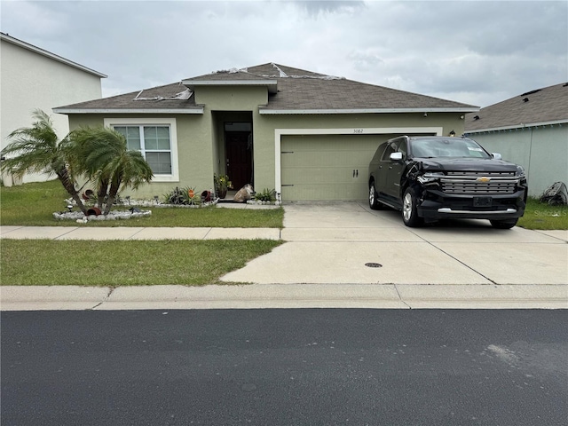 view of front of property featuring driveway, an attached garage, roof with shingles, and stucco siding