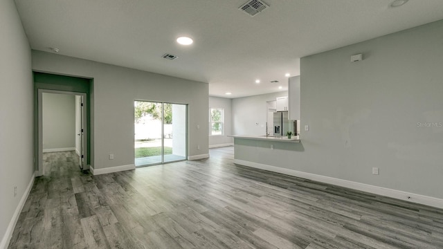 unfurnished living room featuring recessed lighting, visible vents, baseboards, and wood finished floors