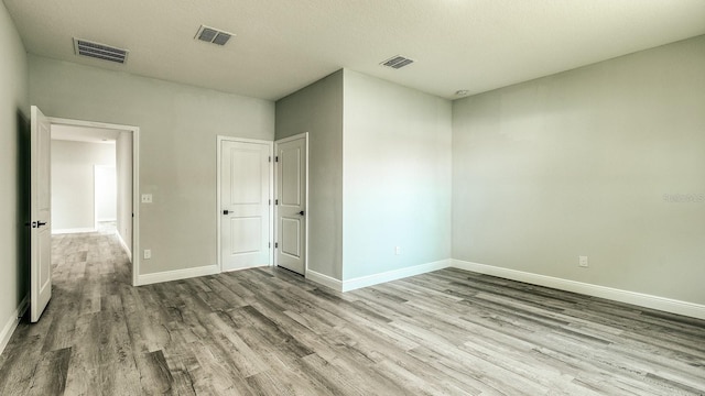 unfurnished bedroom with baseboards, visible vents, and wood finished floors