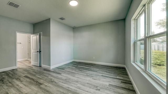 empty room with visible vents, baseboards, and wood finished floors