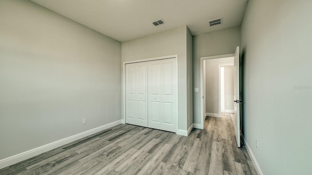 unfurnished bedroom with wood finished floors, visible vents, and baseboards