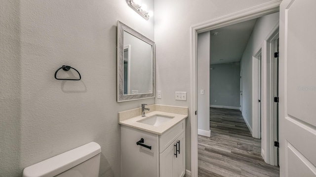 bathroom featuring wood finished floors, vanity, toilet, and baseboards