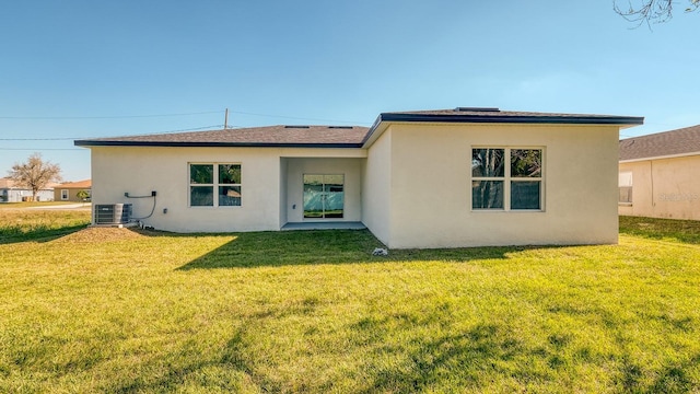 back of house with central AC, a lawn, and stucco siding