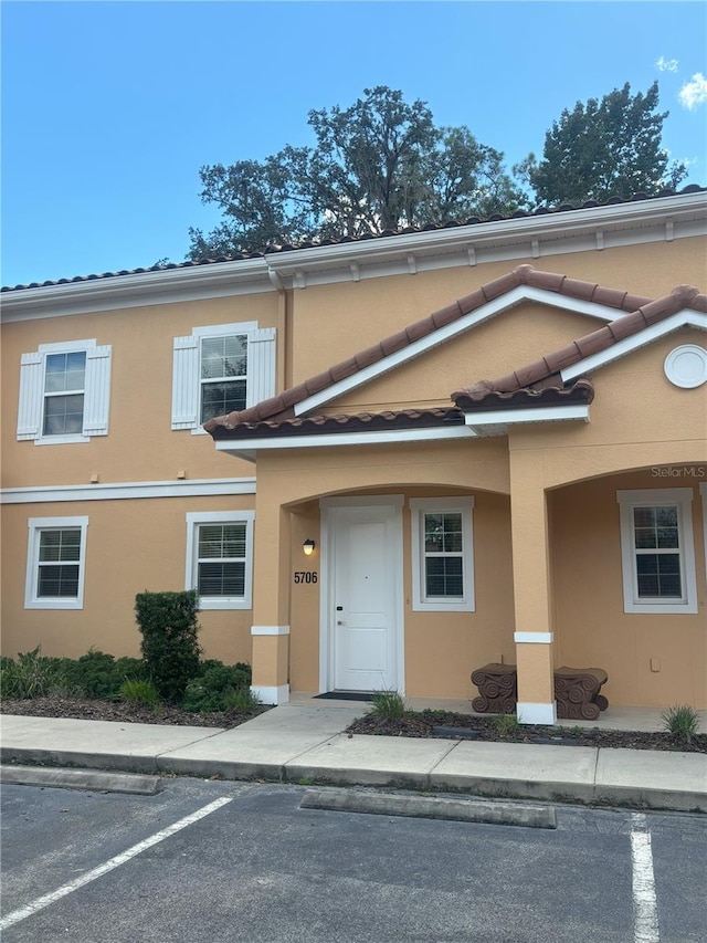 view of front of house featuring uncovered parking, a tiled roof, and stucco siding