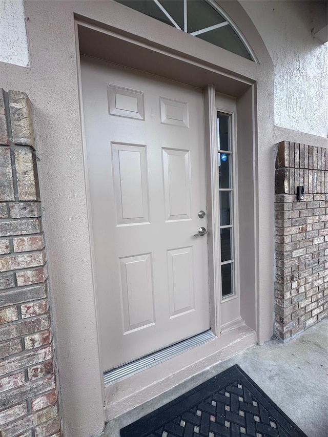 entrance to property featuring brick siding and stucco siding