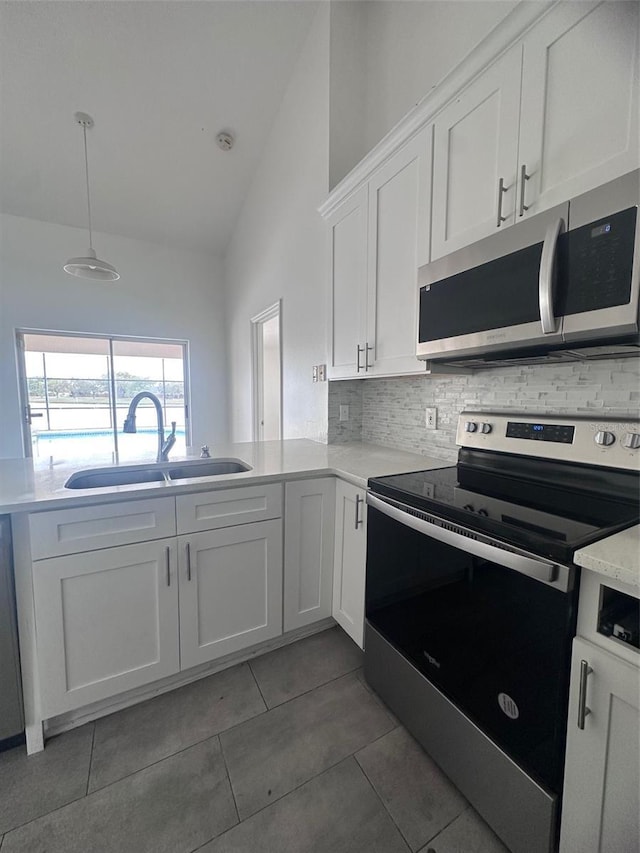 kitchen with stainless steel appliances, a sink, white cabinets, light countertops, and tasteful backsplash