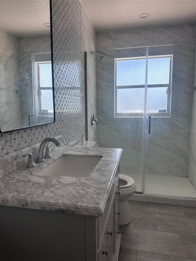 bathroom featuring a stall shower, a textured ceiling, toilet, and vanity