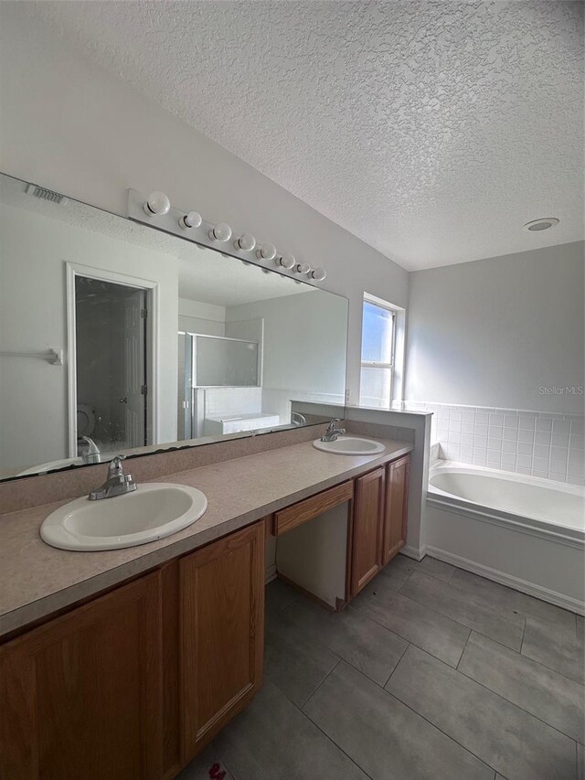 bathroom featuring double vanity, a shower stall, a sink, and a bath